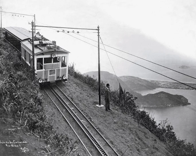 Early electric train climbing the Corcovado tracks with Guanabara Bay in the background, historic photo