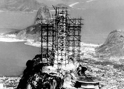 The Christ the Redeemer statue under construction, covered in scaffolding, with Sugarloaf Mountain behind, historic photo